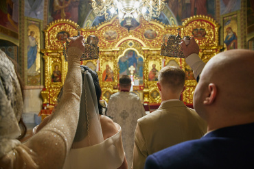 Фотограф на Венчание в Киеве: Сакральная Красота Вашей Любви

Венчание — это не просто красивый обряд, это момент духовного единения, который намного интимнее и глубже, чем официальная роспись в ЗАГСе. Мерцание свечей, запах ладана, тихие молитвы и торжественная тишина старинных сводов создают неповторимую атмосферу. Чтобы передать это на фотографиях, недостаточно просто нажать на кнопку. Профессиональный фотограф на венчание в Киеве — это художник, который умеет писать светом, сохраняя святость момента и не нарушая таинства.

Почему Съемку Венчания Нельзя Доверить Любителю?

Церковь — одна из самых сложных локаций для съемки, и вот почему присутствие профессионала здесь критически важно:

Работа со Специфическим Светом
В храмах Киева часто царит полумрак. Свет от свечей создает глубокие тени и золотистые блики. Смартфоны и любительские камеры здесь бессильны: кадры получаются зернистыми, темными или смазанными. Я использую топовую полнокадровую технику и светосильную оптику, что позволяет снимать **без использования вспышки**. Это сохраняет естественную, таинственную атмосферу храма и объем изображения.

Знание Обряда и Этикет
Фотограф на венчании должен знать ход литургии наперед: когда встать на колени, когда священник поведет пару вокруг аналоя, а когда будут надевать венцы. Профессионал знает, где можно стоять, а куда заходить запрещено, чтобы не помешать молитве и не вызвать недовольство священнослужителей. Главный принцип здесь — быть незаметным.

Художественность и Детали
Венчание соткано из деталей: горящие свечи в руках, обручальные кольца, короны над головами, иконы и расписные своды. Важно не упустить эти мелочи, ведь именно они формируют историю дня.

Самые Красивые Храмы Киева для Венчания: Выбор Локации

Киев богат невероятной архитектурой. Выбор храма влияет на настроение фотографий:
* **Выдубицкий монастырь:** Уютный, старинный, очень теплый и "намоленный" храм с красивой территорией для прогулки после церемонии.
* **Владимирский собор:** Величественный, с богатой росписью и глубокими синими тонами в интерьере.
* **Михайловский Златоверхий монастырь:** Светлый, небесно-голубой, создающий ощущение легкости и торжества.
* **Андреевская церковь:** Жемчужина барокко, идеально подходящая для эстетичных и возвышенных церемоний.
* **Кирилловская церковь:** Уникальная древняя архитектура и фрески для ценителей истории.

Что Входит в Услугу Фотографа на Венчание?

Обычно съемка занимает от 1 до 2 часов.
1.  **Репортаж Таинства:** Съемка всей церемонии от входа в храм до выхода. Все ключевые моменты будут запечатлены с разных ракурсов.
2.  **Постановочные Портреты:** После обряда мы обязательно сделаем серию художественных портретов пары в интерьере храма (с благословения батюшки) и на территории церкви.
3.  **Семейные Фото:** Теплые снимки с родителями, крестными и самыми близкими людьми, которые разделили с вами этот день.

Советы Парам перед Венчанием
* **Одежда:** Выбирайте наряды, прикрывающие плечи. Светлые платки и платья выглядят на фото более воздушно и гармонично, работая как естественный отражатель света, подсвечивая лицо.
* **Макияж:** Для венчания лучше подходит естественный, стойкий макияж. Избегайте слишком жирных текстур, так как в храме может быть жарко от свечей.
* **Настроение:** Забудьте о камерах. Смотрите друг на друга, слушайте священника, проживайте этот момент. Искренность — лучшее украшение ваших снимков.

Венчальные фотографии — это то, что вы будете показывать своим внукам, рассказывая историю вашей семьи. Позвольте мне сохранить для вас этот свет, тепло и святость.

